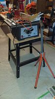 Full view of Durex industrial table saw on metal stand with orange extension cord on top and some tools around it.