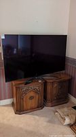 Front view of 65-inch LG TV on curved metal stand with remote on cabinet