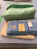 Stacked view of two blankets showing green and blue blankets with label and tag visible