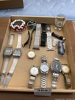 Top-down overview of cardboard tray containing watches, bracelets, bands, tool and spare parts