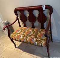 Front angle view of the wood framed bench showing floral upholstered seat and backrest details.