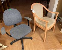 Photo shows side by side a grey office chair with fabric seat, back, and armrests on a black base with casters, and a painted wooden armchair with beige fabric upholstery and visible stains.