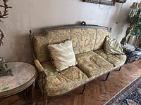 Three-quarter view of full couch showing carved frame, upholstery pattern and two accent pillows.