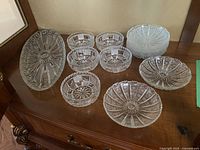 Group view of all crystal items: platter, five bowls, and eight side plates on wooden surface