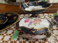 Covered rectangular dish with floral and gold detailing from the front and side views showing intricate design and feet.