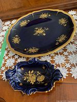 Photo showing both the large Rosenthal plate in dark blue with gold flowers and the smaller Limoges dish with sculptural edges