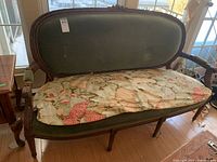Front view of love seat showing full green upholstered back, carved crest and floral seat mat
