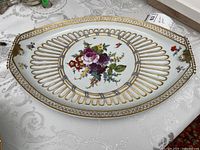 Overhead view showing full platter, central floral bouquet, reticulated rim and both gilt handles