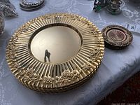 Stack of gold-tone metal chargers with fluted floral borders