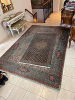 Full view of larger teal and smaller dark Persian-style rugs in entryway