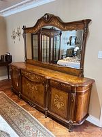 Photo showing the sideboard with wood inlay on top and front, curved design, and attached matching mirror with ornate wood frame