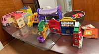 Overview of lot items on table, including Play sets, dollhouse, stroller, and other toys