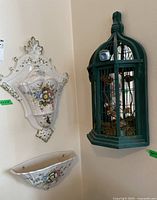 Photo of the larger ceramic piece and the wooden birdcage mounted on adjacent walls