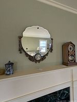 Wide view of the antique beveled edge wall mirror mounted on a wall above a mantel with decorative objects around.