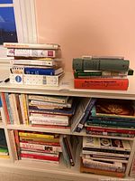 Cookbooks stacked on a shelf with visible titles and colors of covers.