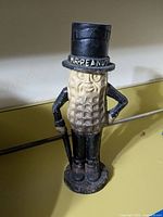 Front view of the Mr. Peanut cast iron bank showing the character in a black top hat and cane with visible paint wear.