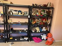 Front view of two black plastic shelving units holding various items such as framed pictures, stuffed toys, and other small collectibles (contents not included).