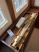 Full view of silver-plated soprano saxophone assembled in wooden case with yellow felt lining, cloth and mouthpiece removed.