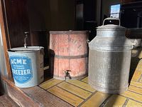 Three-item grouping showing ice cream freezer at left, wooden dispenser center, milk can right