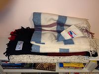 Stack of three blankets: top Landau check blanket, middle buffalo plaid, bottom knit wool
