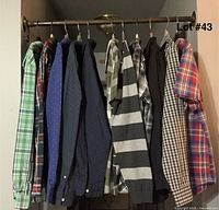 11 men's shirts hanging on rod, variety of plaid and patterned button-up and casual shirts