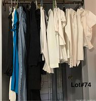 Photo showing clothes hanging including blue tank top, jeans, black tops, white tops and vests