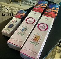 Three diamond art kits on table showing packaging and labeling with titles and sizes.