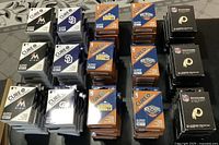 Multiple stacks of unopened sports team band-aids boxes including Miami Marlins, San Diego Padres, Denver Nuggets, and Washington Redskins.