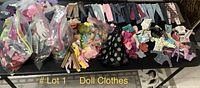 Photo showing a wide variety of small doll clothes and accessories in plastic bags and displayed on a table