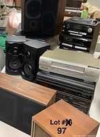 Wide view of stacked vintage audio and video equipment with pair of black speakers on top and wooden speakers in front.