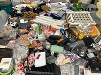 Photo showing a large assortment of miscellaneous items including bags, household parts, decorative items, and electronic accessories spread on a table.