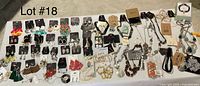 Full overhead view of all 84 pieces laid out on a white surface including earrings, necklaces, bracelets, rings, and hair clip