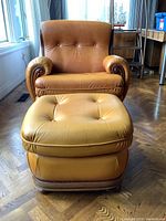 Front view of leather armchair and ottoman on wood parquet floor
