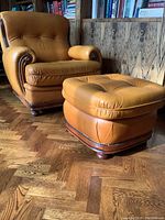 Full view of cognac leather armchair with matching ottoman on parquet floor