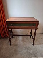 Front view of teak desk showing green panel drawer front and overall shape