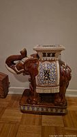 Full side view of the large ceramic elephant plant stand showing detailed glaze work and motifs.