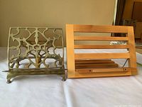 Full view of both vintage book stands side by side on a white surface. Brass stand on left with openwork design, wooden stand on right with horizontal slats.