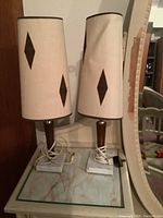 Photo of two vintage MCM table lamps on marble table showing fabric shades with diamond cutouts and square marble bases.