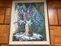 Full view of framed painting resting on parquet floor