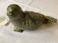 Front view of green stone seal sculpture showing head and body.