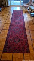 Full-length view of red wool runner on parquet floor showing entire pattern