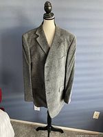 Front view of men's grey textured evening jacket on a mannequin, showing three-button closure, notch lapels, and pockets.