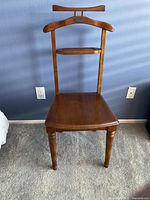 Full view of the wooden jacket chair showing hanger-style top, small shelf and seat