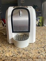 Front view of white jewelry cleaner with stainless steel panel and small cleaning tray area.
