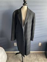 Front view of London Fog men's dark gray wool coat on mannequin against blue wall.