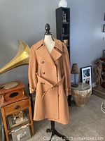 Camel colored men's coat displayed on a dress form, showing full length and button details.