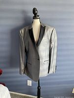 Front view of light gray men's evening jacket with black satin lapels on dress form