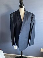 Front view of navy blue men's suit jacket displayed on mannequin.