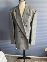 Front view of men's grey double-breasted suit jacket on mannequin, showing button arrangement and fit.