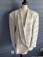 Front view of the white Oscar De La Renta tuxedo jacket showing double-breasted buttons and embroidered lapel.